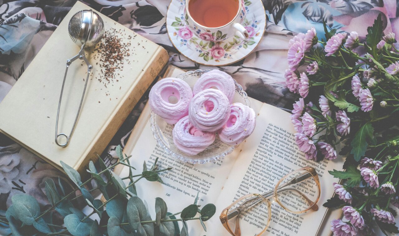 a pretty table filled with books and sweet snacks and a cup of tea.