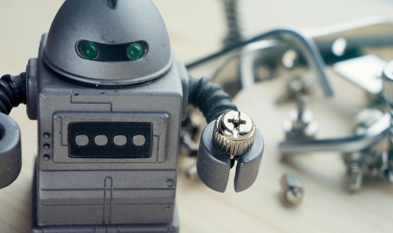 an image of a toy robot holding a nut sitting on a work bench.