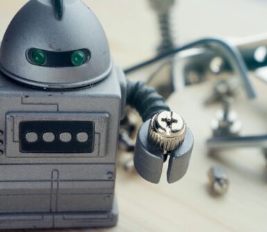 an image of a toy robot holding a nut sitting on a work bench.