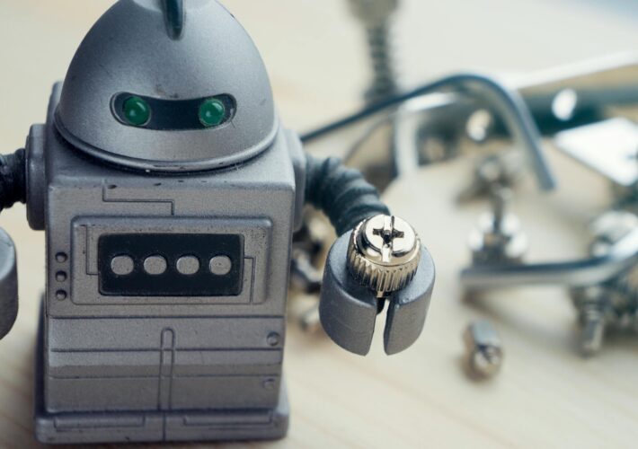 an image of a toy robot holding a nut sitting on a work bench.