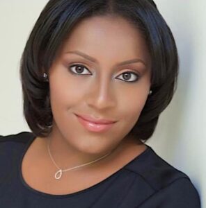 Smiling Black woman with short, straight black hair and neutral makeup, wearing a black top and a delicate necklace.
