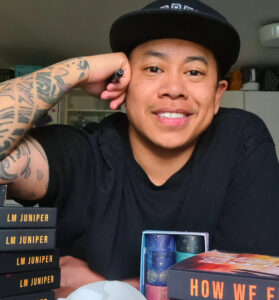 image L.M. Juniper - a trans indonesian author posing by his books 